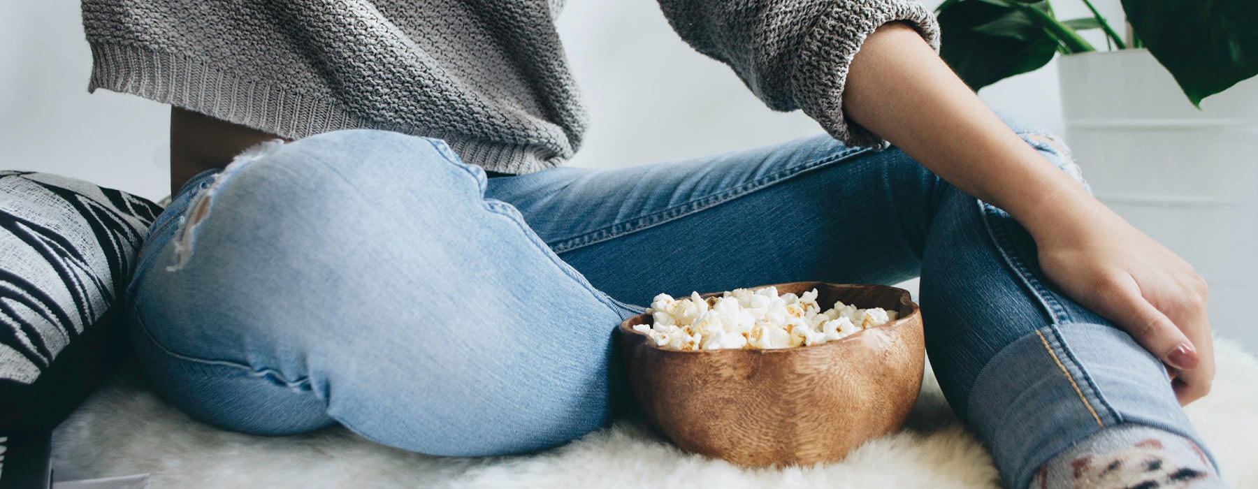 woman sits on rug with a bowl of popcorn